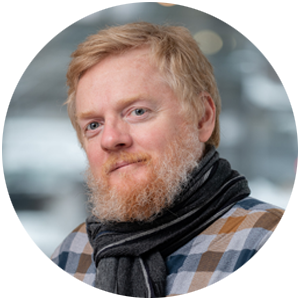 Headshot of a man with beard wearing a scarf and plaid shirt